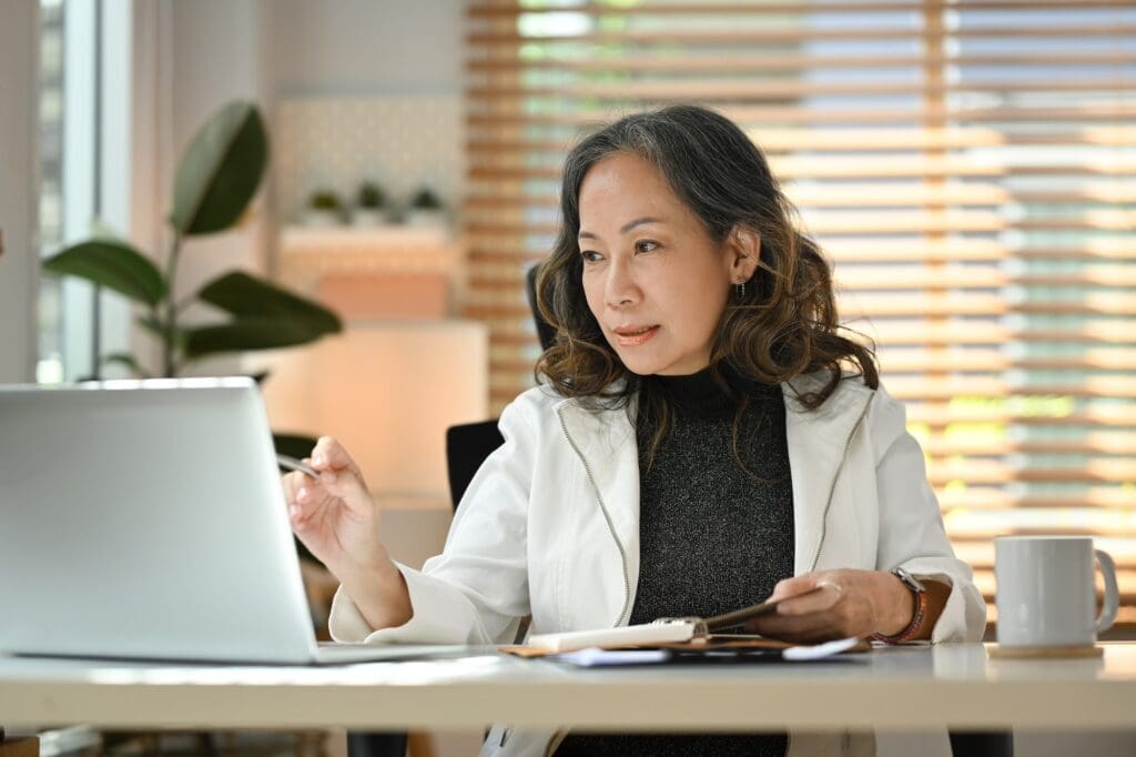 Elegant mature business woman remote working from home, watching online webinar.
