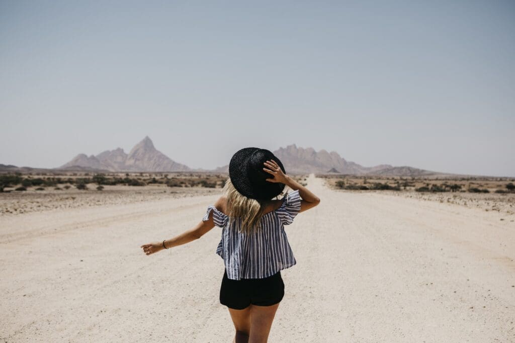 Namibia, woman walking on the road to Spitzkoppe