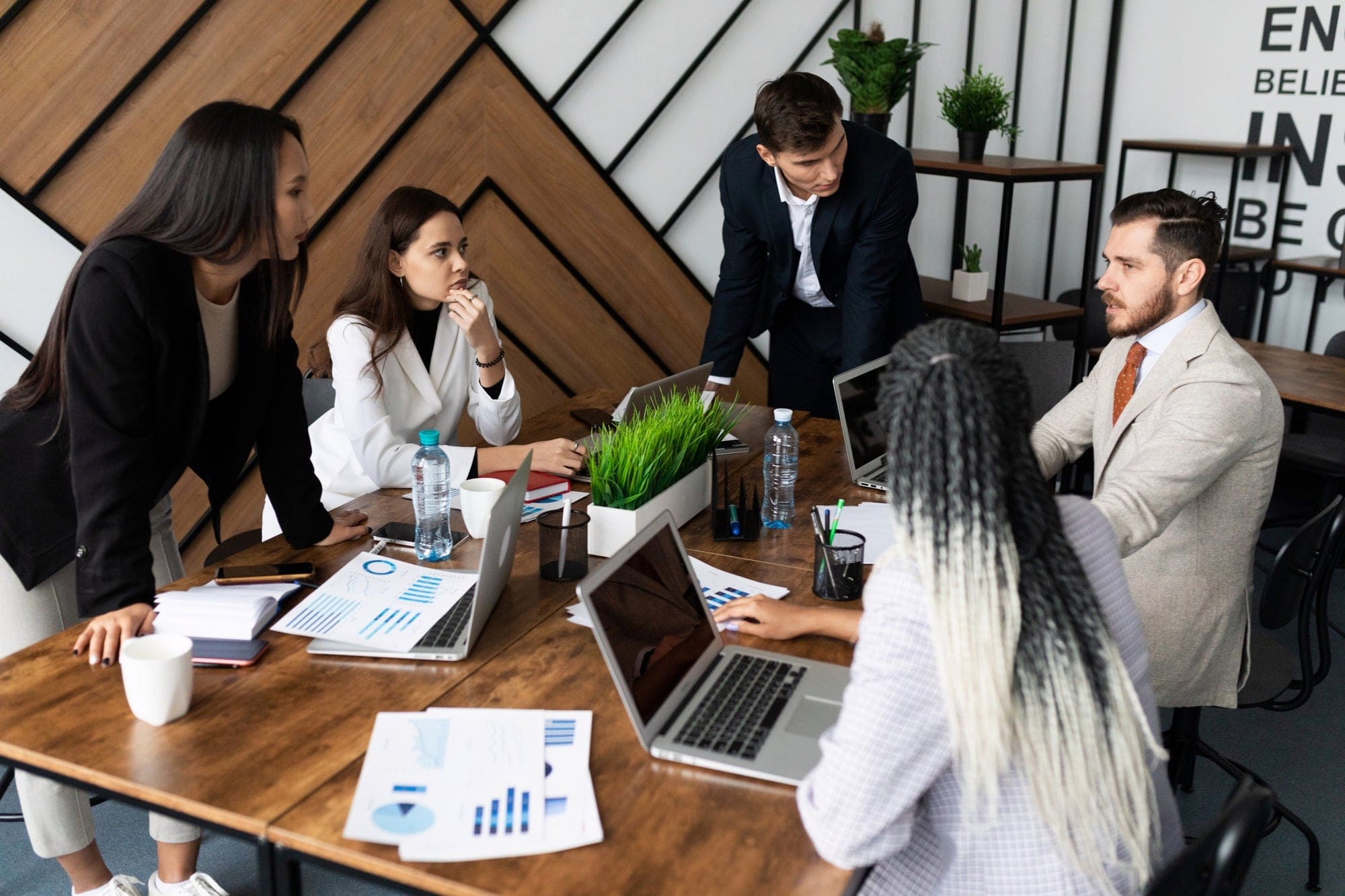 Marketing team. Group of young modern people in smart casual wear discussing something while working